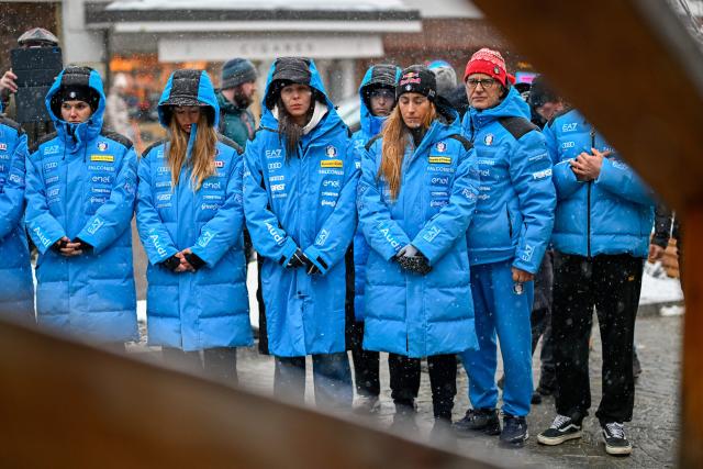 Members of the Italy's alpine skiing team taking part in the World Cup races in Crans Montana, with Women's Technical Director Gianluca Rulfi (R), and Sofia Goggia (2nd R) stand in front of the bar "Le Constellation" to pay tribute to the victims of the fire that ripped through the venue on New Year's Eve celebrations, in the Alpine ski resort of Crans-Montana on January 28, 2026. The fire on January 1 at the bar "Le Constellation" left 40 people dead -- including nine French and six Italian nationals -- and injured 116 others, most of them teenagers. (Photo by Fabrice COFFRINI / AFP)