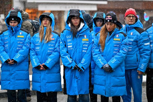 Women's Technical Director Gianluca Rulfi (R), Sofia Goggia (2nd R) and others members of the Italy's alpine skiing team taking part in the World Cup races in Crans Montana, stand in front of the bar "Le Constellation" to pay tribute to the victims of the fire that ripped through the venue on New Year's Eve celebrations, in the Alpine ski resort of Crans-Montana on January 28, 2026. The fire on January 1 at the bar "Le Constellation" left 40 people dead -- including nine French and six Italian nationals -- and injured 116 others, most of them teenagers. (Photo by Fabrice COFFRINI / AFP)