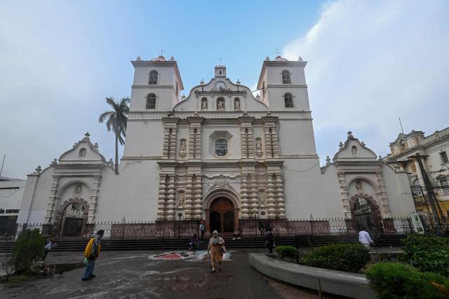 People walk past the facade of the St. Michael the Archangel Cathedral in Tegucigalpa on January 28, 2026. (Photo by Johan ORDÓÑEZ / AFP)