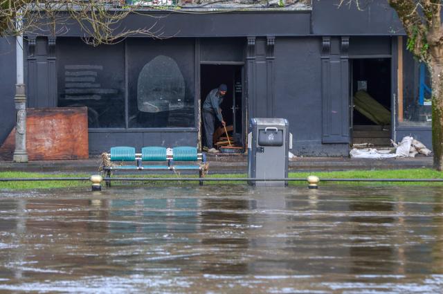A person clears flood water from a shop near the bank of the raised River Slaney, after the river burst its banks during Strom Chandra, in Enniscorthy, near Wexford, south east Ireland on January 28, 2026. (Photo by Paul Faith / AFP)