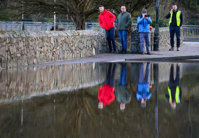 People look at flood water covering a road, after the River Slaney burst its banks during Storm Chandra, in Enniscorthy, near Wexford, south east Ireland on January 28, 2026. (Photo by Paul Faith / AFP)
