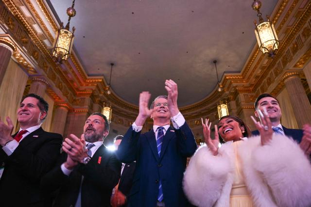 Dell CEO Michael Dell (L), US Secretary of Treasury Scott Bassent (C) and Trinidadian rapper and singer-songwriter Nicki Minaj, applaude as US President Donald Trump arrives to speaks about 'Trump Accounts' at the Andrew W. Mellon Auditorium in Washington, DC, on January 28, 2026. (Photo by Brendan SMIALOWSKI / AFP)