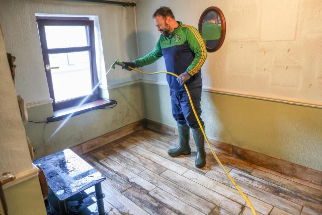 A person works uses a hose to wash river water off the internal walls of a property after the River Slaney burst its banks flooding the property during Strom Chandra, in Enniscorthy, near Wexford, south east Ireland on January 28, 2026. (Photo by Paul Faith / AFP)