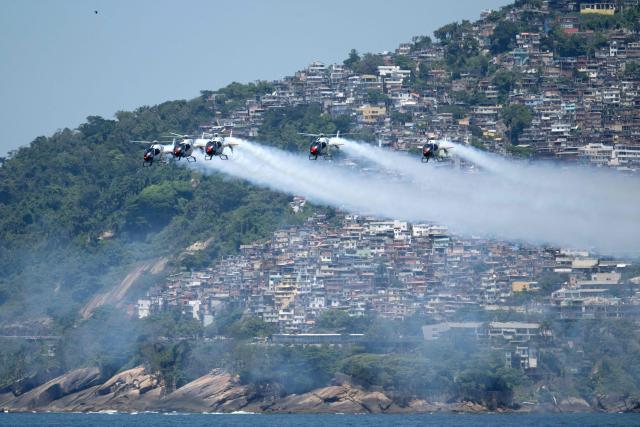 Helicopters from the Spanish Air and Space Force's ASPA patrol perform an aerial display over Ipanema Beach in Rio de Janeiro, Brazil on January 28, 2026. The event makes the centenary of the 1926 Plus Ultra flight, the first single-aircraft crossing of the South Atlantic from Spain to South America. (Photo by Pablo PORCIUNCULA / AFP)