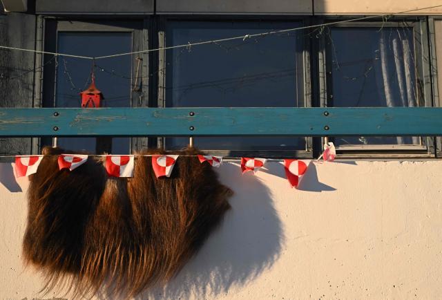 Greenlandic flags hang next to a skin of a Musk-ox on a balcony of an apartment in the city of Nuuk, western Greenland, on January 28, 2026. (Photo by Ina FASSBENDER / AFP)