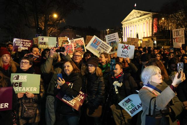 Protesters hold placards as they take part in a rally against Donald Trump's policies in front of the National Assembly in Paris on January 28, 2026. On January 24, federal agents shot and killed Alex Pretti, a 37-year-old ICU nurse, while scuffling with him on an icy roadway in Minneapolis, less than three weeks after an immigration officer fired on Renee Good, also 37, killing her in her car. The killings capped months of escalating violence in which masked, unidentified and heavily armed ICE and border patrol agents have grabbed people they accuse of violations off the streets. (Photo by Dimitar DILKOFF / AFP)