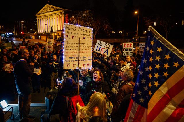 Protesters hold placards as they take part in a rally against US President Donald Trump's policies in front of the National Assembly in Paris on January 28, 2026. On January 24, federal agents shot and killed Alex Pretti, a 37-year-old ICU nurse, while scuffling with him on an icy roadway in Minneapolis, less than three weeks after an immigration officer fired on Renee Good, also 37, killing her in her car. The killings capped months of escalating violence in which masked, unidentified and heavily armed ICE and border patrol agents have grabbed people they accuse of violations off the streets. (Photo by DIMITAR DILKOFF / AFP)