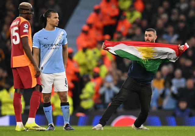 Pitch invaders waving flags stop the the UEFA Champions League football match between Manchester City and Galatasaray at the Etihad Stadium in Manchester, north west England, on January 28, 2026. (Photo by Oli SCARFF / AFP)