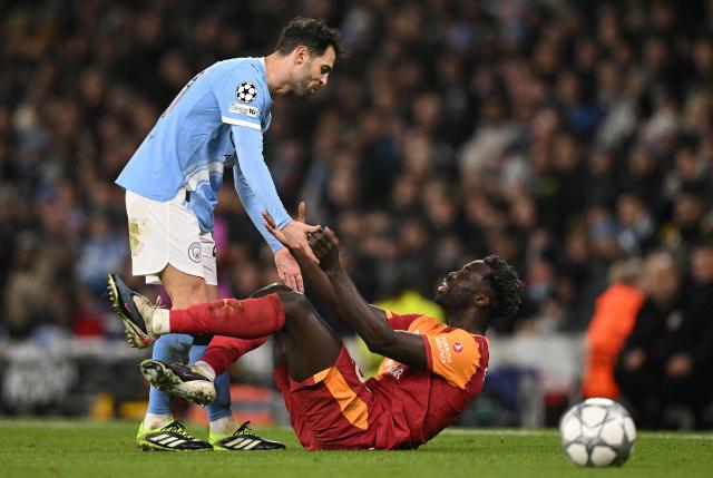 Manchester City's Portuguese midfielder #20 Bernardo Silva helps Galatasaray's Colombian defender #06 Davinson Sanchez back up to his feet during the UEFA Champions League football match between Manchester City and Galatasaray at the Etihad Stadium in Manchester, north west England, on January 28, 2026. (Photo by Oli SCARFF / AFP)