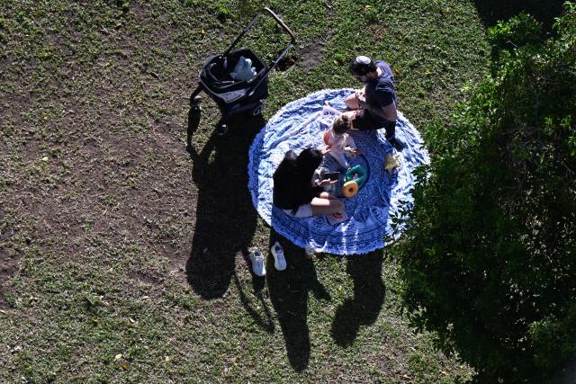 A family rests at the France Square in San Jose on 28 January 2026. Right-wing politician Laura Fernandez appears set to win Costa Rica's presidential election in the first round, according to two opinion polls published on January 21. (Photo by Marvin RECINOS / AFP)