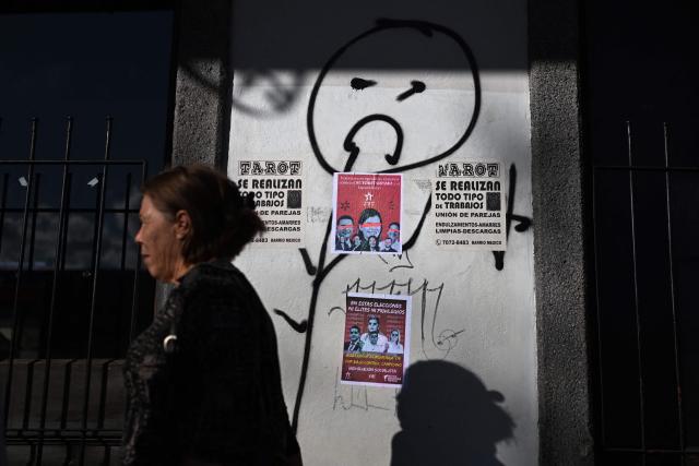 A woman walks past a political poster that reads in Spanish, "In these elections, no elites or privileges," on a wall in San Jose on January 28, 2026. Right-wing politician Laura Fernandez appears set to win Costa Rica's presidential election in the first round, according to two opinion polls published on January 21. (Photo by MARVIN RECINOS / AFP)