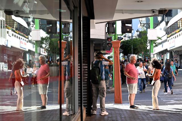 People walk through downtown in San Jose on 28 January 2026. Right-wing politician Laura Fernandez appears set to win Costa Rica's presidential election in the first round, according to two opinion polls published on January 21. (Photo by Marvin RECINOS / AFP)