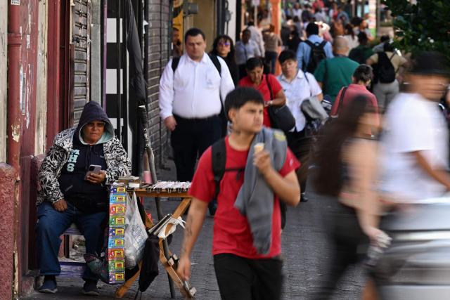 A street vendor is seen while people walk through downtown in San Jose on 28 January 2026. Right-wing politician Laura Fernandez appears set to win Costa Rica's presidential election in the first round, according to two opinion polls published on January 21. (Photo by Marvin RECINOS / AFP)