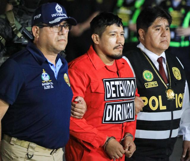 Interpol and Peruvian police officers escort Erick Moreno Hernandez (C), known as ‘The monster,’ who arrives after being extradited from Paraguay at the Police Aviation Directorate (DIRAVPOL) in Collao, Peru, on January 28, 2026. One of the main leaders of an organization dedicated to extortion and contract killings in Peru arrived in Lima on January 28, extradited from Paraguay to serve a 32-year sentence, an AFP journalist reported. Erick Moreno, leader of ‘Los Injertos del Cono Norte,’ had been imprisoned in Asunciуn since last September, when Paraguayan authorities captured him after a three-year manhunt. (Photo by Connie FRANCE / AFP)