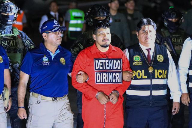 Peruvian police officers escort Erick Moreno Hernandez (C), known as ‘The monster,’ who arrives after being extradited from Paraguay at the Police Aviation Directorate (DIRAVPOL) in Collao, Peru, on January 28, 2026. One of the main leaders of an organization dedicated to extortion and contract killings in Peru arrived in Lima on January 28, extradited from Paraguay to serve a 32-year sentence, an AFP journalist reported. Erick Moreno, leader of ‘Los Injertos del Cono Norte,’ had been imprisoned in Asunciуn since last September, when Paraguayan authorities captured him after a three-year manhunt. (Photo by Connie FRANCE / AFP)