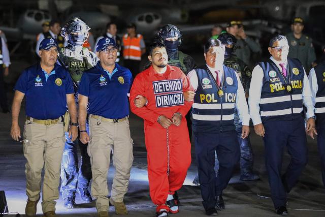 Peruvian police officers escort Erick Moreno Hernandez (C), known as ‘The monster,’ who arrives after being extradited from Paraguay at the Police Aviation Directorate (DIRAVPOL) in Collao, Peru, on January 28, 2026. One of the main leaders of an organization dedicated to extortion and contract killings in Peru arrived in Lima on January 28, extradited from Paraguay to serve a 32-year sentence, an AFP journalist reported. Erick Moreno, leader of ‘Los Injertos del Cono Norte,’ had been imprisoned in Asunciуn since last September, when Paraguayan authorities captured him after a three-year manhunt. (Photo by Connie FRANCE / AFP)