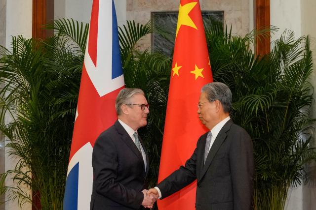 Zhao Leji (R), Chairman of the Standing Committee of China’s National People’s Congress (NPC), shakes hands with Britain's Prime Minister Keir Starmer at the Great Hall of the People in Beijing on January 29, 2026. Starmer arrived on January 28 for the first visit by a British prime minister to China since 2018, seeking to promote what he called "pragmatic" partnership with the Asian giant after years of fraught relations. (Photo by Kin Cheung / POOL / AFP)