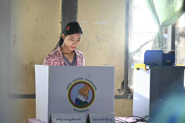 (FILES) A woman casts her vote at a polling station during the second phase of Myanmar's general election at Kawhmu township in Yangon on January 11, 2026. The colour of the winning party in Myanmar's junta-run election is the same green as a general's uniform, its staff are retired senior officers, and most expect it to march in lockstep with the military. The Union Solidarity and Development Party (USDP) claimed an overwhelming victory that indicates the country's armed forces, known as the Tatmadaw, intend to preserve their grip on power. But the top brass' decision to cloak its command in civilian dress means ceding some of junta chief Min Aung Hlaing's singular authority, analysts say. (Photo by Sai Aung MAIN / AFP)