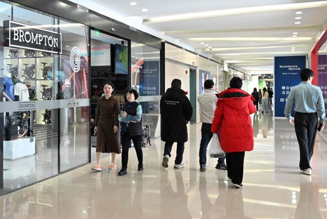 People walk past a British Brompton folding bicycle shop in Beijing on January 29, 2026. (Photo by Adek BERRY / AFP)