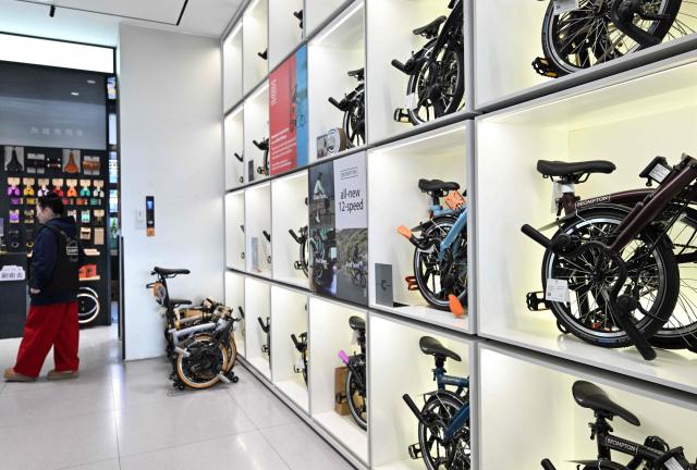 Shop attendants wait for customers at a British Brompton folding bicycle shop in Beijing on January 29, 2026. (Photo by Adek BERRY / AFP)
