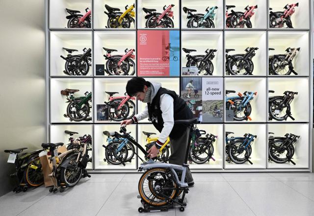 A shop attendant unfolds a British Brompton folding bicycle at a shop in Beijing on January 29, 2026. (Photo by Adek BERRY / AFP)
