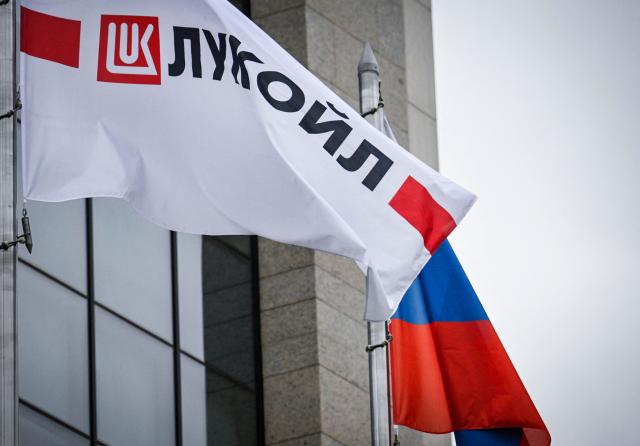(FILES) Russia's Lukoil oil giant logo banners and a Russian National Flag flutter on Lukoil headquarters building in Moscow on October 23, 2025. Russia's oil giant Lukoil, sanctioned by Washington over the Ukraine war, said on January 29, 2026 that it will sell its foreign assets to the US investment firm The Carlyle Group. (Photo by Alexander NEMENOV / AFP)