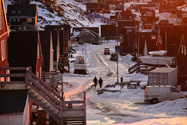 A couple walks in a snow covered street of the old city in Nuuk, western Greenland, on January 28, 2026. (Photo by Ina FASSBENDER / AFP)