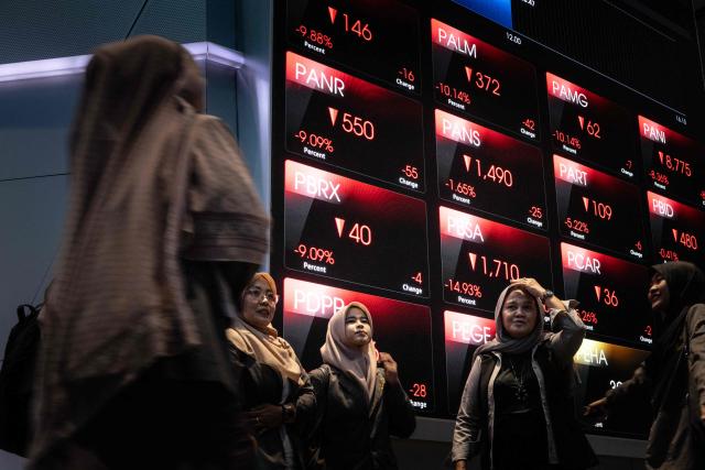 Visitors take pictures in front of an electronic board displaying stock prices at the Indonesia Stock Exchange (IDX) in Jakarta on January 29, 2026. (Photo by YASUYOSHI CHIBA / AFP)
