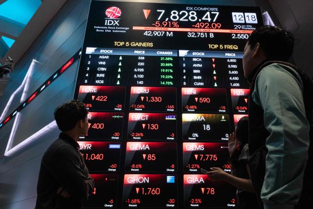 People look at an electronic board displaying stock prices at the Indonesia Stock Exchange (IDX) in Jakarta on January 29, 2026. (Photo by YASUYOSHI CHIBA / AFP)