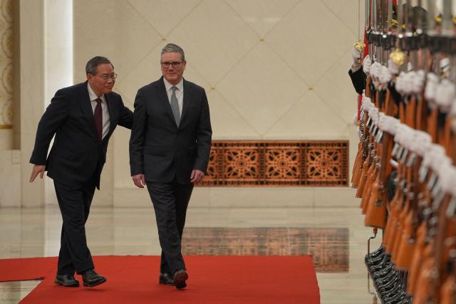 Chinese Premier Li Qiang (L) and Britain's Prime Minister Keir Starmer inspect a Chinese honour guard during a welcome ceremony at the Great Hall of the People in Beijing on January 29, 2026. Chinese President Xi Jinping told Starmer their countries must "strengthen" ties to counter geopolitical headwinds, as the leaders met in Beijing on January 29. (Photo by Kin Cheung / POOL / AFP)