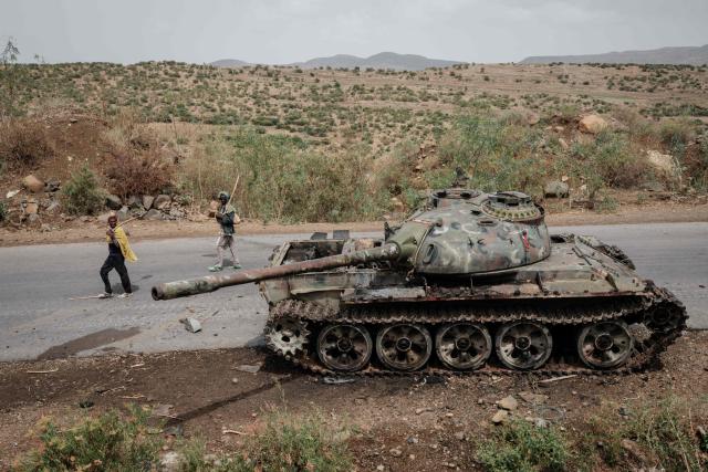 (FILES) Local farmers walk next to a tank of alledged Eritrean army that is abandoned along the road in Dansa, southwest of Mekele in Tigray region, Ethiopia, on June 20, 2021. Clashes between federal and Tigrayan forces have erupted in Ethiopia's northern Tigray region, prompting the suspension of flights, security and diplomatic sources told AFP on January 29, 2026.
Hostilities broke out in Tsemlet, western Tigray, an area claimed by forces from the neighbouring Amhara region, the sources told AFP on condition of anonymity. (Photo by Yasuyoshi CHIBA / AFP)