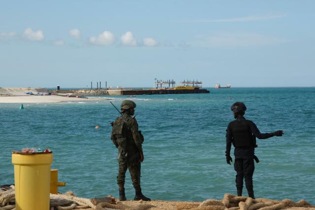(FILES) A Rwandan policeman (R) and a Rwandan soldier guard The Total Mozambique LNG Project in Afungi in the Cabo Delgado province, Mozambique, on September 29, 2022. Mozambique said it would hold a ceremony on January 29, 2026 to relaunch a massive gas project led by French energy giant TotalEnergies that had been on hold for around five years after a deadly jihadist attack.
President Daniel Chapo will formally announce the restart of the Mozambique LNG project at a ceremony attended by TotalEnergies chief executive Patrick Pouyanne, the government said. (Photo by Camille LAFFONT / AFP)