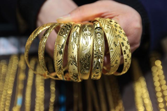 A staff member displays gold jewelry at a gold store in Lianyungang, in China’s eastern Jiangsu province on January 29, 2026. Gold prices soared to another fresh record above 5,500 USD on January 29. (Photo by AFP) / China OUT