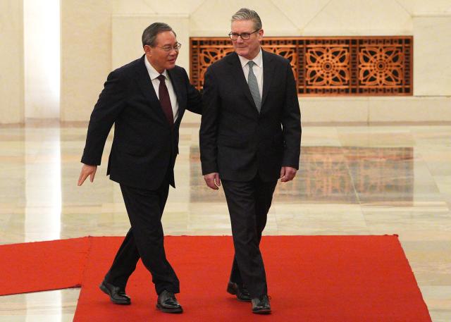 Chinese Premier Li Qiang (L) and Britain's Prime Minister Keir Starmer inspect a Chinese honour guard during a welcome ceremony at the Great Hall of the People in Beijing on January 29, 2026. Chinese President Xi Jinping told Starmer their countries must "strengthen" ties to counter geopolitical headwinds, as the leaders met in Beijing on January 29. (Photo by Carl Court / POOL / AFP)