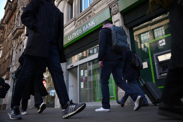 Pedestrians walk past a branch of a Lloyds bank in London on January 29, 2026. Lloyds Banking Group said on January 29 that its net profit rose six percent last year as higher income offset compensation for consumers caught up in a UK car loans scandal. Profit after tax grew to £4.76 billion ($6.58 billion) in 2025 from £4.48 billion a year earlier, the company said in a statement. (Photo by Henry NICHOLLS / AFP)