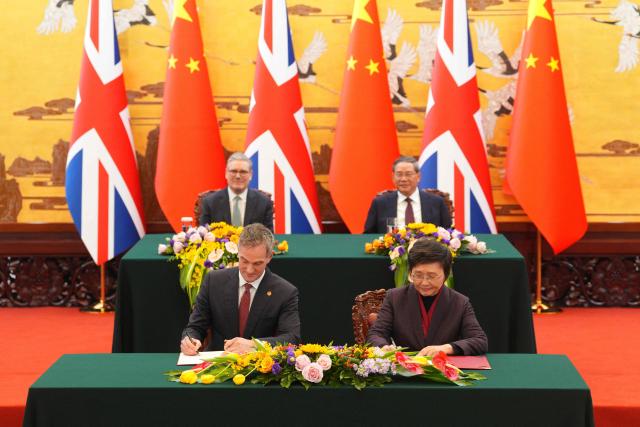 Britain's Prime Minister Keir Starmer and Chinese Premier Li Qiang (R) look on as British Business Secretary Peter Kyle and Wang Xiaoping, Minister of Human Resources and Social Security, sign a Memorandum of Understanding following a bilateral meeting at the Great Hall of the People in Beijing on January 29, 2026. (Photo by Carl Court / POOL / AFP)