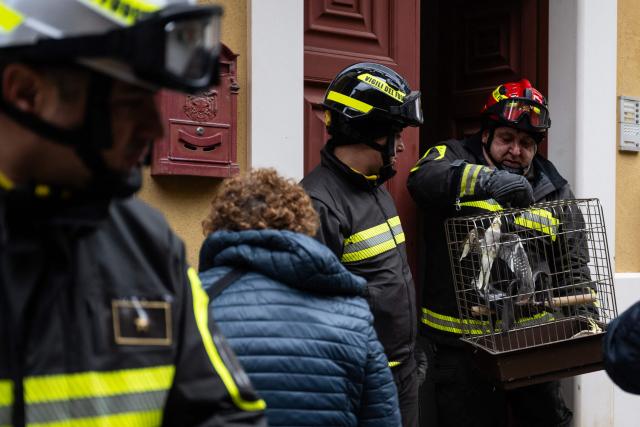 Firefighters help evacuees to rescue parrots from a house and to collect their belongings in the red zone of Niscemi, Sicily, on January 29, 2026. A large area of the town of Niscemi is declared  "red zone" after the a 4km-long stretch of the hillside collapsed on January 25, 2026, forcing the evacuation of some 1,500 people. The town, built on unstable terrain, was battered by a powerful storm which hit southern Italy last week and experts say the chasm could widen further and swallow houses with the rains expected over the coming days. (Photo by MARCO BERTORELLO / AFP)