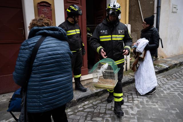 Firefighters help evacuees to rescue parrots from a house and to collect their belongings in the red zone of Niscemi, Sicily, on January 29, 2026. A large area of the town of Niscemi is declared  "red zone" after the a 4km-long stretch of the hillside collapsed on January 25, 2026, forcing the evacuation of some 1,500 people. The town, built on unstable terrain, was battered by a powerful storm which hit southern Italy last week and experts say the chasm could widen further and swallow houses with the rains expected over the coming days. (Photo by MARCO BERTORELLO / AFP)