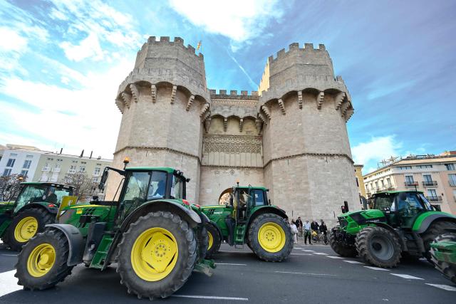 TOPSHOT - Tractors drive past Serranos Towers monument during a farmers protest against the EU-Mercosur trade deal and the economic pressures facing the agricultural sector in Valencia, on January 29, 2026. (Photo by Jose JORDAN / AFP)