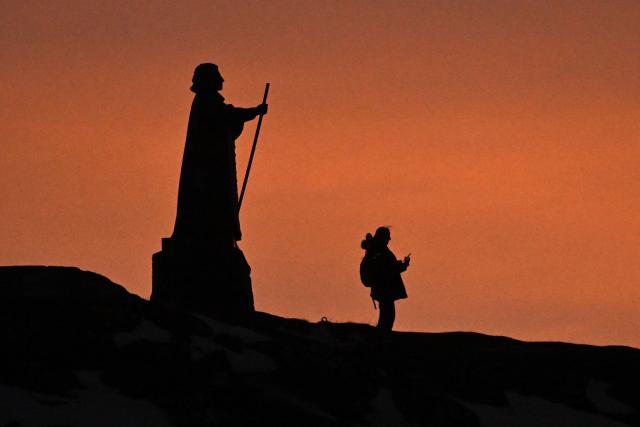 A woman takes a photo next to the statue of Hans Egede, a Norwegian Lutheran priest and missionary who launched mission efforts to Greenland, in Nuuk, Greenland on January 29, 2026. (Photo by Ina FASSBENDER / AFP)