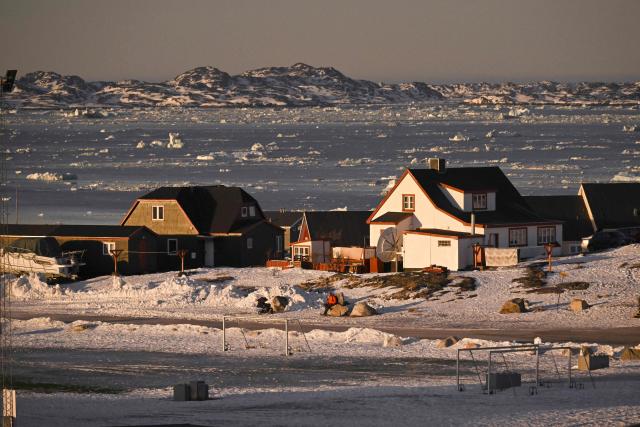 A woman sits on a stone at a residential area in front of the coastline with ice blocks in the city of Nuuk, Greenland on January 29, 2026. (Photo by Ina FASSBENDER / AFP)