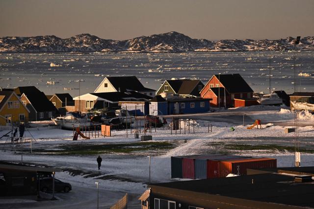A man walks past a playground at a residential area in front of the coastline with ice blocks in the city of Nuuk, Greenland, on January 29, 2026. (Photo by Ina FASSBENDER / AFP)