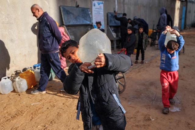 A young boy carries a container filled with water from a public cistern in the Nuseirat camp for Palestinian refugees north of Deir al-Balah in the central Gaza Strip on January 29, 2026. Since October 10, a fragile US-sponsored truce in Gaza has largely halted the fighting between Israeli forces and Hamas, but both sides have alleged frequent violations. (Photo by EYAD BABA / AFP)