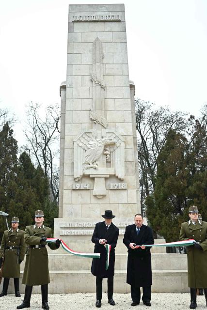 Hungarian Defence Minister Kristof Szalay-Bobrovniczky (C-L) and the President of the Budapest Jewish Community (BZSH) Tamas Mester (C-R) cut the ribbon in national colours as Hungarian government officials and Jewish community leaders take part in a ceremonial unveiling of completely renovated war memorials at the largest Jewish cemetery in Budapest, Hungary, on January 29, 2026. The monuments are dedicated to Jewish soldiers who died fighting for Austro-Hungary in World War I and to the unknown victims of forced labour in World War II. (Photo by Attila KISBENEDEK / AFP)