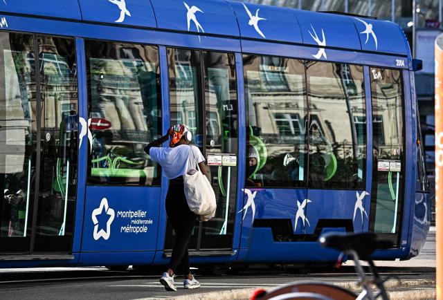 A pedestrian walks past a tramway in Montpellier, southern France, on January 29, 2026. Free transportation is a popular idea for the March municipal elections in many cities. But the promises vary greatly, and some candidates denounce it as “vote fishing” or even a “false good idea.” Initially limited to young people and seniors, then to weekends, this promise made in 2020 for Montpellier has, for a little over two years now, been available on buses and trams to all 500,000 residents of this metropolitan area. (Photo by Gabriel BOUYS / AFP)