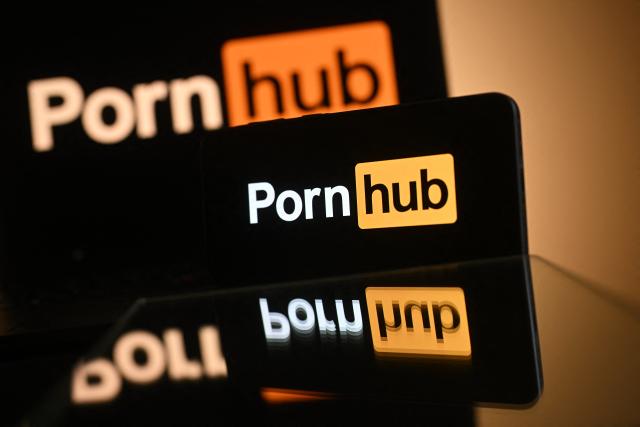 An illustration photograph taken on January 29, 2026 shows the logo of the website Pornhub, arranged for a photograph on a laptop and smartphone, at a residential property in Guildford, south of London. Cyprus-based Aylo, the adult content giant which owns Pornhub, YouPorn and Redtube, said on January 27 it will block new users in Britain from February 2, citing the protection of minors. New UK rules since July require porn sites to carry out strict age verification checks through tools such as facial imagery or credit card identification -- or face hefty fines. (Photo by Justin TALLIS / AFP)