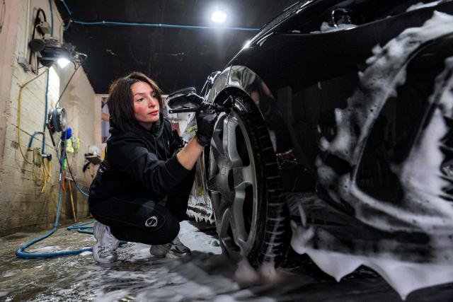 Hanadi Hadya, a 36-year-old Palestinian woman who opened her own carwash, brushes the rims of a vehicle at her shop in Beit Jala in the centre of the occupied West Bank on January 29, 2026. (Photo by HAZEM BADER / AFP)