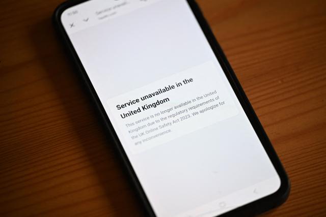 An illustration photograph taken on January 29, 2026 shows a smartphone displaying information about the UK Online Safety Act, at a residential property in Guildford, south of London. Cyprus-based Aylo, the adult content giant which owns Pornhub, YouPorn and Redtube, said on January 27 it will block new users in Britain from February 2, citing the protection of minors. New UK rules since July require porn sites to carry out strict age verification checks through tools such as facial imagery or credit card identification -- or face hefty fines. (Photo by Justin TALLIS / AFP)
