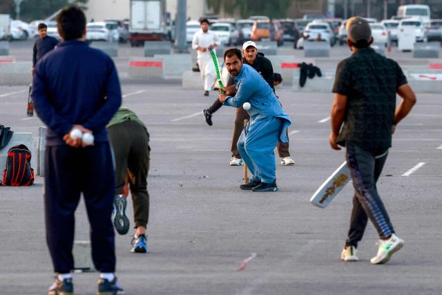 Members of Qatar's Pakistani community play cricket at a car park at sunset in Doha on January 29, 2026. (Photo by Karim JAAFAR / AFP)