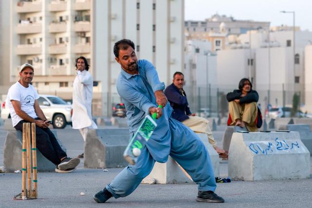 TOPSHOT - Members of Qatar's Pakistani community play cricket at a car park at sunset in Doha on January 29, 2026. (Photo by Karim JAAFAR / AFP)